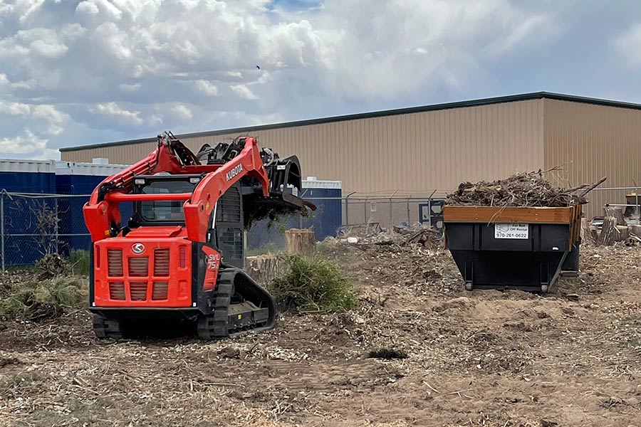 Excavator Putting Yard Cleanup in Dumpster Grand Junction CO
